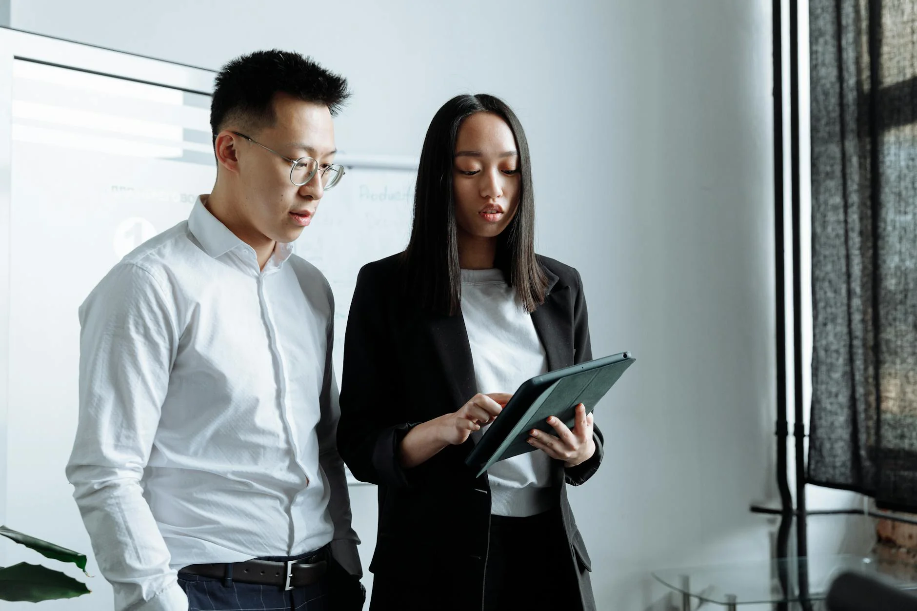 Two professionals reviewing information on a tablet device together in an office setting