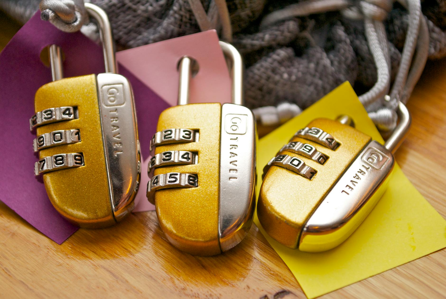 Three gold combination padlocks on coloured paper representing file-locking strategies for AI coding agent protection