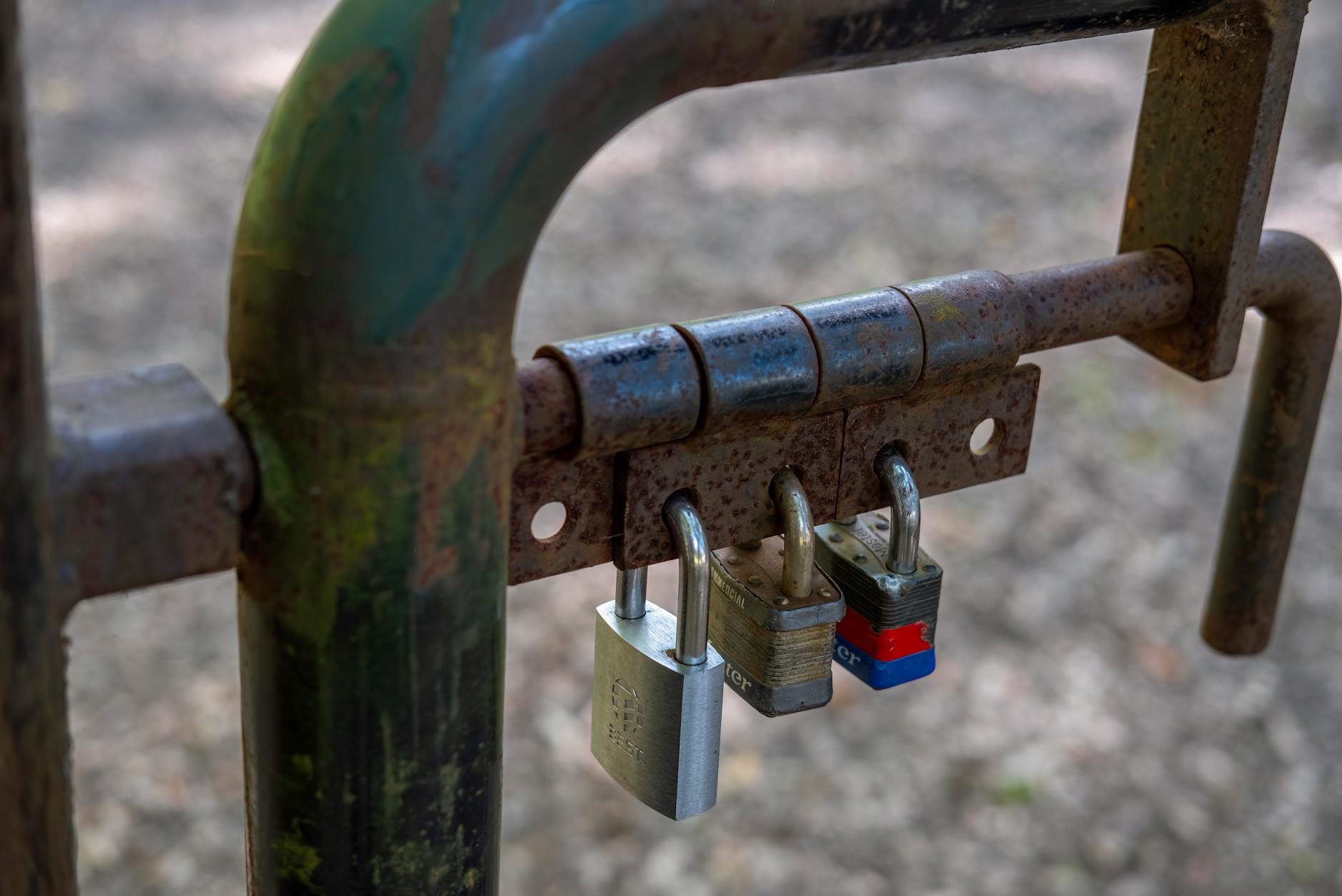 Three padlocks on a rusty hinge representing layered security protection mechanisms