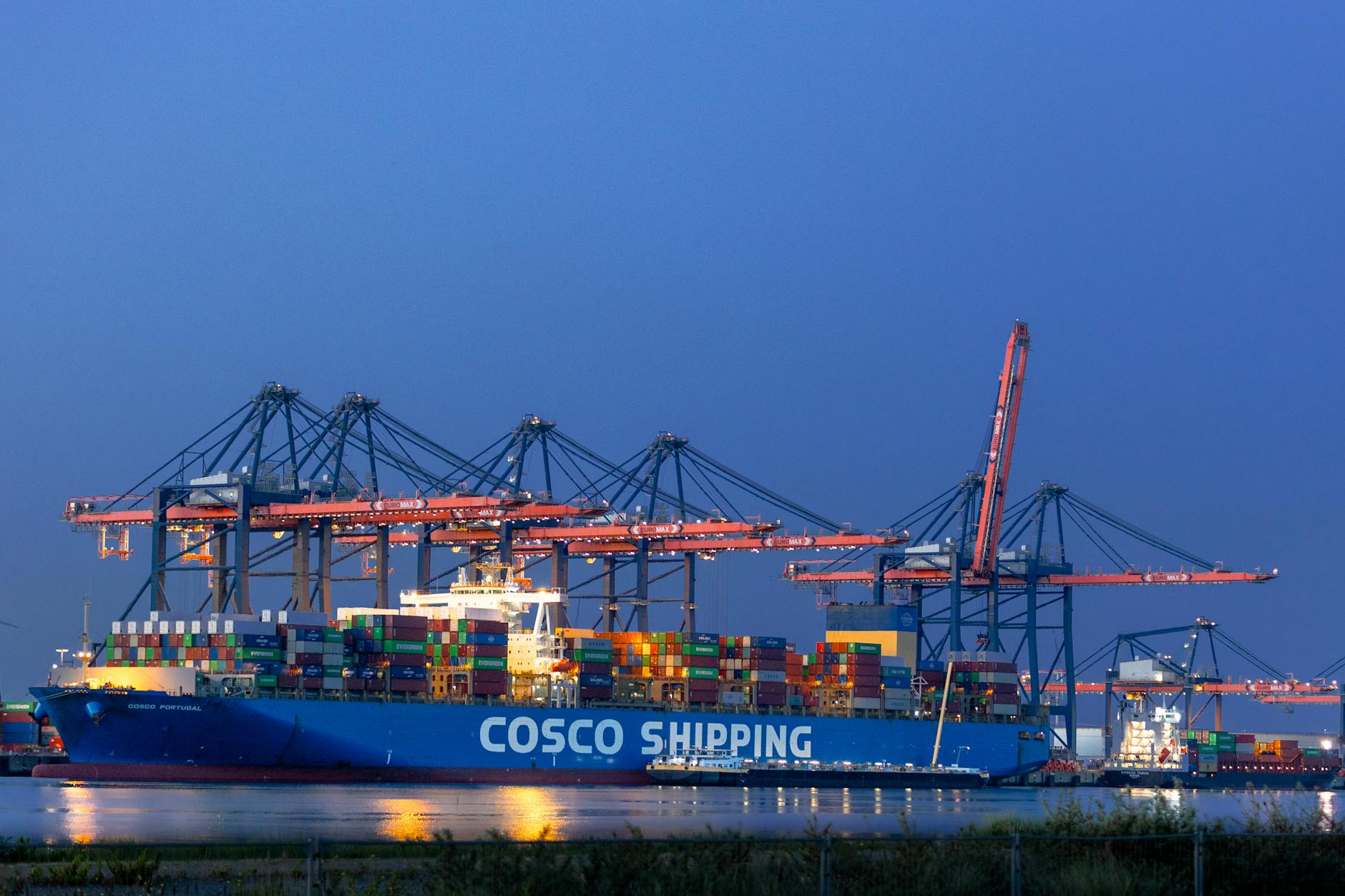 Cargo ship loaded with colourful shipping containers at a port during twilight